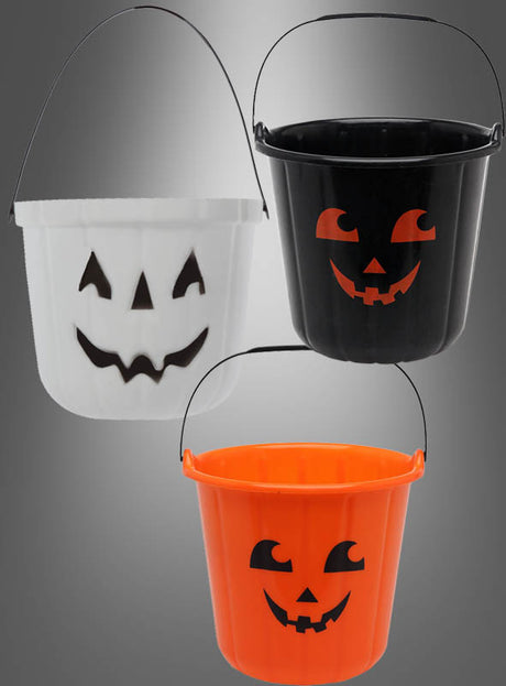 Drei Halloween-Eimer für Süßigkeiten in Weiß, Schwarz und Orange – jeweils mit einem Kürbiskopf-Motiv und einem schwarzen Henkel – sind vor einem Hintergrund mit Farbverlauf abgebildet und eignen sich somit ideal zum Sammeln von Süßigkeiten in der Halloween-Nacht.