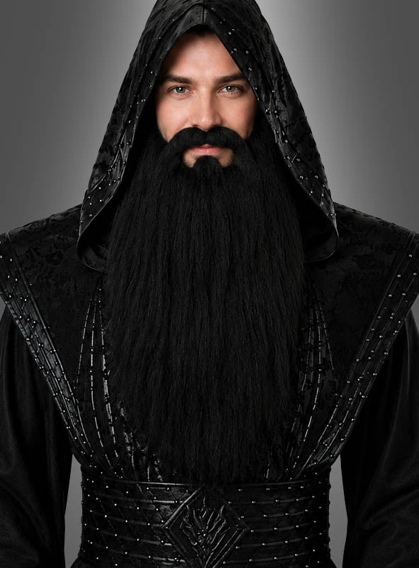 Eine Person, die eine lange schwarze Kapuzenrobe trägt und einen „extra langen Vollbart, schwarz oder weiß“, steht mit dem Gesicht nach vorne vor einem grauen Hintergrund.