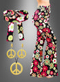 Eine Frau trägt die Schlaghose „Night Flower“ mit Accessoires, die sich durch ein fröhliches Blumenmuster und ein passendes Stirnband auszeichnet, während seitlich goldene Peace-Zeichen-Ohrringe und eine Halskette zu sehen sind.