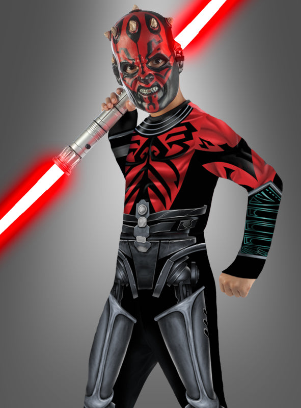 Ein Kind, das das „Darth Maul Cyborg für Kinder – The Clone Wars“-Kostüm trägt und ein rotes Doppelklingen-Lichtschwert schwingt – mit einer Gesichtsbemalung, die perfekt auf die legendäre Figur abgestimmt ist –, nimmt vor einem grauen Hintergrund eine dynamische Pose ein. Damit ist dieses Kostüm die ideale Wahl für jede Star Wars- oder Clone Wars-Kostümparty.