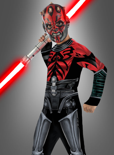 Ein Kind, das das „Darth Maul Cyborg für Kinder – The Clone Wars“-Kostüm trägt und ein rotes Doppelklingen-Lichtschwert schwingt – mit einer Gesichtsbemalung, die perfekt auf die legendäre Figur abgestimmt ist –, nimmt vor einem grauen Hintergrund eine dynamische Pose ein. Damit ist dieses Kostüm die ideale Wahl für jede Star Wars- oder Clone Wars-Kostümparty.