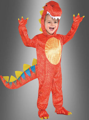 Ein Kind, das das leuchtend rote Dinosaurier-Kinderkostüm „Dinomite“ mit fröhlichen gelben und blauen Stacheln trägt, lächelt und reckt beide Arme in die Höhe, während es vor einem schlichten grauen Hintergrund steht – ideal für Kinderkarnevalsfeiern.