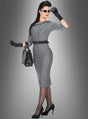 Eine Frau präsentiert das „Jackie Rockabilly“-Bleistiftkleid im Stil der 50er Jahre – ein figurbetontes, kariertes Bleistiftkleid mit Gürtel –, kombiniert mit schwarzen Handschuhen, einer Sonnenbrille, High Heels und einer Handtasche, während sie vor einem grauen Hintergrund mit Farbverlauf posiert.