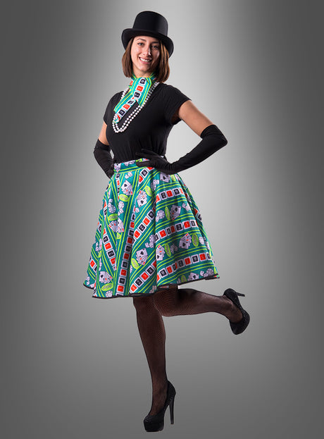 Eine Frau posiert auf einem Bein und trägt einen Zylinder, schwarze Handschuhe, ein schwarzes Oberteil sowie das „Casino Rock“-Halstuch mit einem von Monopoly inspirierten Design. Sie rundet ihr „Glücksspielerin“-Outfit mit Netzstrümpfen und schwarzen High Heels ab und steht selbstbewusst vor einem schlichten grauen Hintergrund.