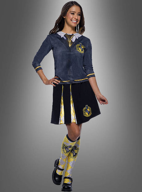 Eine Person, die ein passendes Hogwarts-Schuluniform-Kostüm trägt, steht vor einem grauen Hintergrund. Das Outfit umfasst den „Hufflepuff Rock für Damen“ aus der Harry-Potter-Reihe sowie einen passenden Pullover, eine Krawatte und kniehohe Socken mit dem Hufflepuff-Hauswappen – ein authentisches Ensemble, das perfekt für eingefleischte Fans der Zauberer-Reihe ist.