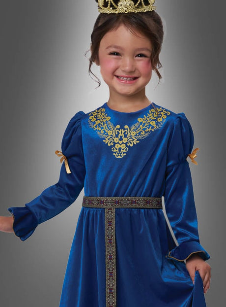 Ein kleines Kind lächelt in seinem „Kleine Renaissance-Prinzessin“-Kostüm – einem blauen Samtkleid mit goldenen Verzierungen und einer Krone – vor einem grauen Hintergrund mit Farbverlauf.