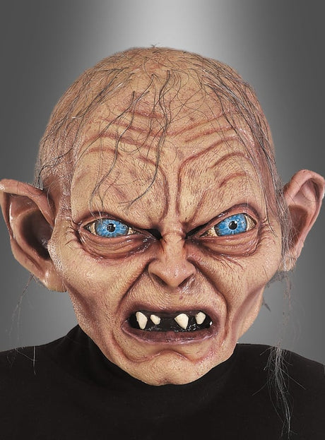 Eine Person, die die „Der Herr der Ringe – Hobbit – Gollum-Latexmaske“ trägt, die sich durch detaillierte, übertriebene Elemente wie große blaue Augen, spitze Ohren, faltige Haut und scharfe Zähne auszeichnet, vor einem grauen Hintergrund mit Farbverlauf.