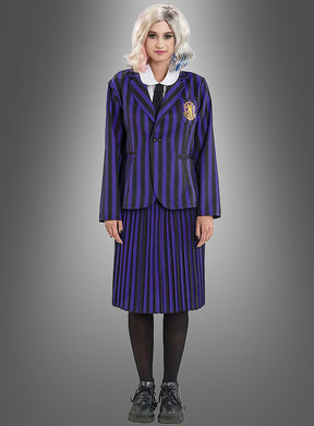 Diese Person trägt das Enid-Kostüm aus „Wednesday“ – bestehend aus einer schwarz-lila gestreiften Schuluniform mit Blazer und Rock, einem weißen Hemd, einer schwarzen Krawatte, schwarzen Strumpfhosen, schwarzen Schuhen und einer weißen Perücke – und verkörpert damit den ikonischen Look der Nevermore Academy, während sie vor einem grauen Hintergrund steht.