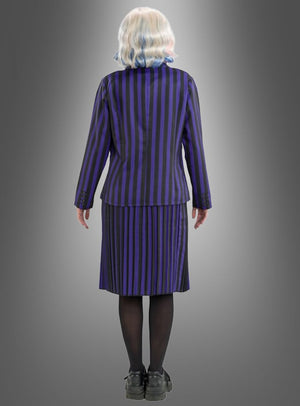 Eine Person mit kurzen, gewellten, weißen Haaren steht mit dem Rücken zur Kamera und trägt das „Enid-Kostüm aus Wednesday“ – ein schwarz-lila gestreiftes Set aus Jacke und Rock –, dazu schwarze Strumpfhosen und schwarze Schuhe, vor einem grauen Hintergrund mit Farbverlauf.