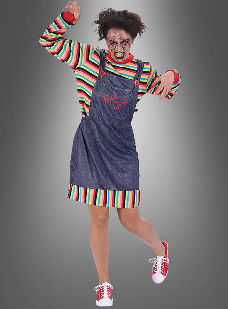 Eine Person, die das „Mörderpuppe“-Kleid für Damen trägt, kombiniert mit einem gestreiften Shirt, einem von einem Chucky-Kostüm inspirierten Jeansoverall, zerzausten Haaren, gruseligem Gesichts-Make-up und roten Schuhen, posiert mit einem erhobenen Arm vor einem grauen Hintergrund.