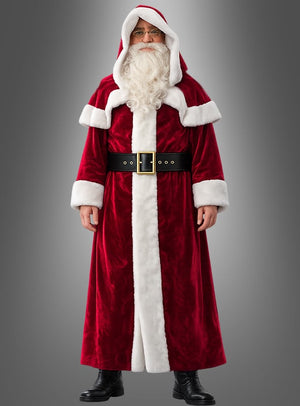 Eine Person, die den „Mantel Weihnachtsmann dunkelrot“ trägt – einen rot-weißen Mantel im Weihnachtsmann-Stil mit Kapuze, schwarzem Gürtel und schwarzen Stiefeln –, steht vor einem grauen Hintergrund.