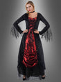 Eine Frau, die das „Vampirin Selina Kleid mit Spitze“ trägt – ein auffälliges schwarz-rotes Kleid im Gothic-Stil mit Spitzenärmeln –, steht mit den Händen in den Hüften vor einem grauen Hintergrund mit Farbverlauf und ist damit das perfekte Halloween-Kostüm als Vampirin oder Halloween-Abendkleid für Damen für eine unvergessliche Nacht.