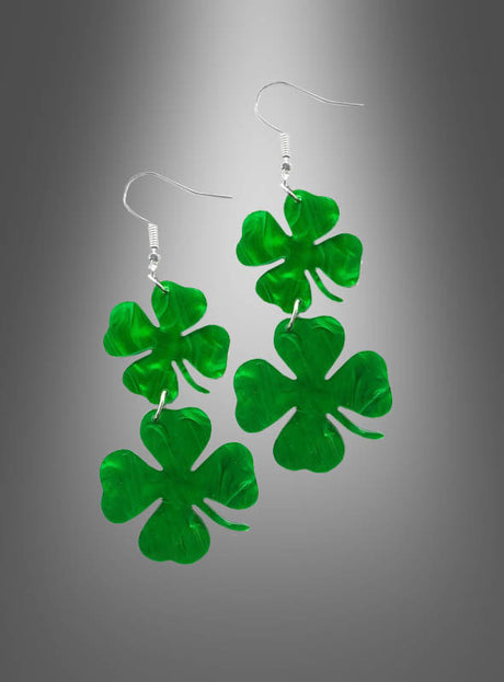 Ein Paar hängende St. Patrick’s Day-Ohrringe in Kleeblattform, jeweils mit zwei grünen vierblättrigen Kleeblatt-Anhängern, dargestellt vor einem grauen Hintergrund mit Farbverlauf.