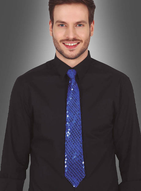 Ein Mann in einem schwarzen Hemd und einer funkelnden blauen Pailletten-Krawatte (Unisex) steht vor einem grauen Hintergrund mit Farbverlauf und lächelt in die Kamera. Dieses auffällige Unisex-Accessoire ist die perfekte Wahl, um jedem Karnevalsoutfit Glanz und Pep zu verleihen.