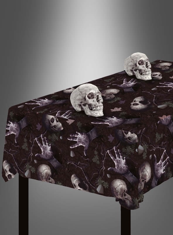 Der Tisch ist mit der abwischbaren Mehrweg-Tischdecke „Totenköpfe“ bedeckt, die ein auffälliges Totenkopfmuster mit Skeletthänden und Knochenmotiven aufweist – die perfekte Halloween-Tischdekoration. Darauf sind zwei realistische Totenkopf-Dekorationen platziert.