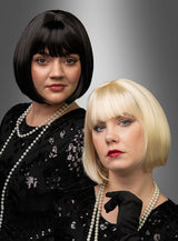 Zwei Frauen mit stilvollen kurzen Bob-Frisuren – die eine trägt die hochwertige Pagenschnitt-Bob-Perücke „Vera“ in glänzendem Schwarz, die andere einen schicken blonden Bob – posieren elegant in schwarzen Paillettenkleidern und mit Perlenketten vor einem grauen Hintergrund mit Farbverlauf.