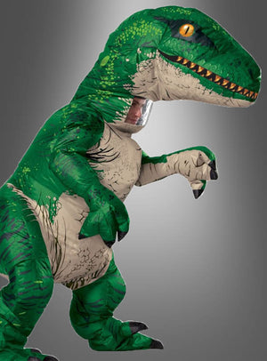 Eine Person, die das „Jurassic World Velociraptor Dino-Kostüm mit Sound“ trägt, steht vor einem schlichten grauen Hintergrund und vermittelt so den typischen Look dieses kultigen aufblasbaren Kostüms.