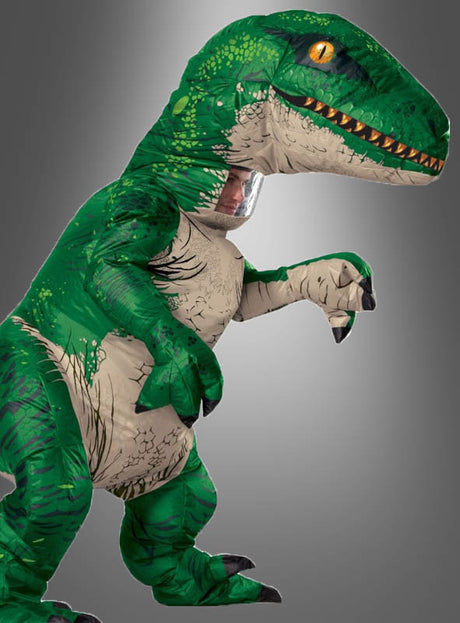 Eine Person, die das „Jurassic World Velociraptor Dino-Kostüm mit Sound“ trägt, steht vor einem schlichten grauen Hintergrund und vermittelt so den typischen Look dieses kultigen aufblasbaren Kostüms.