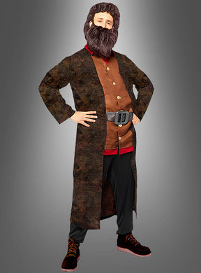 Eine Person im Herren-Hagrid-Kostüm aus Harry Potter – bestehend aus einem langen braunen Mantel, einem braunen Hemd mit goldenen Knöpfen, einem breiten Gürtel, einer dunklen Hose, roten Stiefeln und einem großen braunen Bart – steht mit in die Hüften gestemmen Händen vor einem grauen Hintergrund; das perfekte Outfit für jede Harry-Potter-Kostümparty.