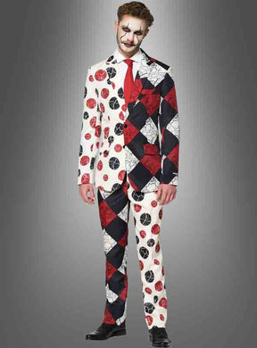 Ein Mann im „Suitmeister Clown-Anzug mit Krawatte“ – bestehend aus einem Anzug im Harlekin-Stil mit kontrastierenden Mustern und Farben, schwarzen Schuhen und Clown-Make-up – steht vor einem grauen Hintergrund mit Farbverlauf – perfekt für alle, die auf der Suche nach einem auffälligen Halloween-Clown-Anzug oder einem einzigartigen Clown-Kostüm für Halloween sind.