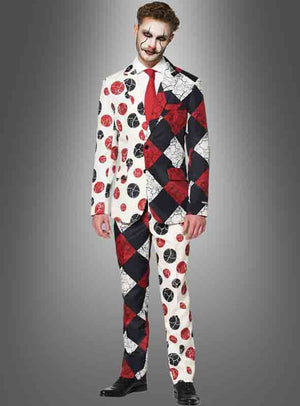 Ein Mann im „Suitmeister Clown-Anzug mit Krawatte“ – bestehend aus einem Anzug im Harlekin-Stil mit kontrastierenden Mustern und Farben, schwarzen Schuhen und Clown-Make-up – steht vor einem grauen Hintergrund mit Farbverlauf – perfekt für alle, die auf der Suche nach einem auffälligen Halloween-Clown-Anzug oder einem einzigartigen Clown-Kostüm für Halloween sind.