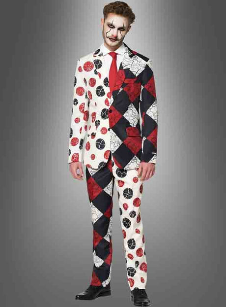 Ein Mann im „Suitmeister Clown-Anzug mit Krawatte“ – bestehend aus einem Anzug im Harlekin-Stil mit kontrastierenden Mustern und Farben, schwarzen Schuhen und Clown-Make-up – steht vor einem grauen Hintergrund mit Farbverlauf – perfekt für alle, die auf der Suche nach einem auffälligen Halloween-Clown-Anzug oder einem einzigartigen Clown-Kostüm für Halloween sind.