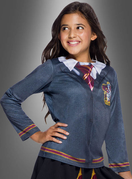 Ein Mädchen mit langen dunklen Haaren trägt das fotorealistische Gryffindor-Shirt aus der Harry-Potter-Reihe, das im Stil einer klassischen Hogwarts-Uniform gestaltet ist. Vor einem grauen Hintergrund lächelt sie und posiert mit einer Hand in der Hüfte.