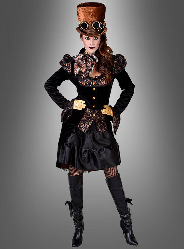 Eine Frau in einem Steampunk-Kostüm mit einem hohen braunen Zylinder, einer Schutzbrille, einem schwarzen Kleid mit goldenen Akzenten, goldenen Handschuhen und kniehohen schwarzen Stiefeln – ihr Look wird durch die auffällige Steampunk-Jacke „Lady Herriet“ im viktorianischen Stil abgerundet – posiert vor einem grauen Hintergrund mit Farbverlauf.