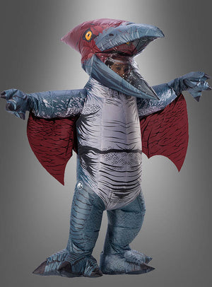 Eine Person trägt ein blau-rotes, aufblasbares Pteranodon-Kostüm mit ausgebreiteten Flügeln und steht vor einem schlichten grauen Hintergrund.