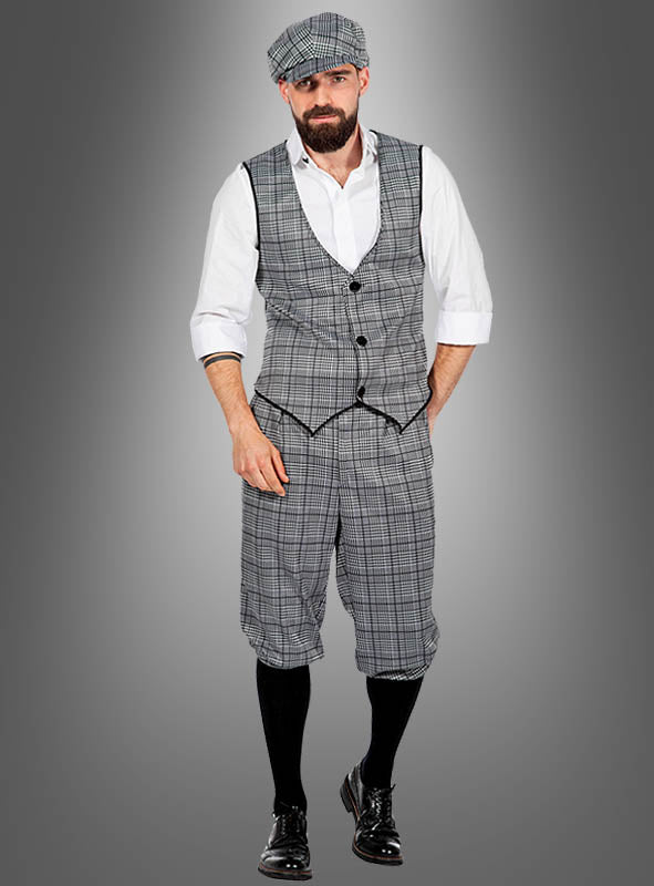 Ein Mann im „20er-Jahre-Kostüm für Herren Michael“ – bestehend aus einer karierten Mütze, einer dazu passenden karierten Weste, einer Knickerbocker-Hose, einem weißen Hemd, schwarze Socken und schwarze Schuhe – steht vor einem schlichten Hintergrund mit Farbverlauf und ist damit die ideale Wahl für alle, die ein authentisches „Peaky Blinders“-Kostüm oder ein Herren-Outfit im Stil der 20er Jahre suchen.