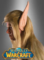 Eine Person, die eine lange blonde Perücke und große „Elfenohren“-Prothesen aus „World of Warcraft“ trägt, den Blick nach links gerichtet, mit einem „World of Warcraft“-Horde-Logo am unteren Rand – ein offizielles, von Blizzard lizenziertes Produkt.