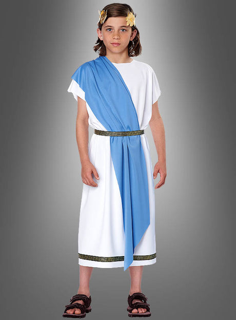 Ein Kind, gekleidet in die „Römer Toga für Kinder“ – mit weißer Tunika, blauer Schärpe, goldenem Gürtel und einem Lorbeerkranz als Kopfschmuck – steht vor einem grauen Hintergrund mit Farbverlauf und eignet sich somit ideal als römisches Kostüm für Mottopartys und Veranstaltungen.