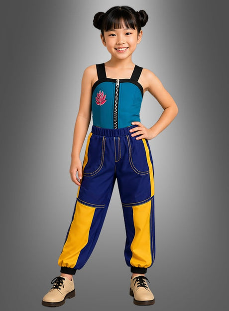 Ein kleines Kind steht lächelnd da, gekleidet im „Cooles K-Pop Star Zomy“-Kostüm für Kinder – ein blaugrünes Oberteil mit Reißverschluss, schwarzen Trägern und einem Lotus-Motiv, eine blau-gelbe Cargohose sowie beige Stiefel – und posiert vor einem grauen Hintergrund mit Farbverlauf für einen stilvollen, vom Pop inspirierten Look.