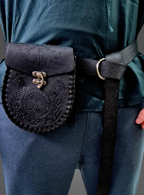 Eine Person, die ein dunkelgrünes Hemd und eine blaue Hose trägt und an der Taille eine schwarze, geprägte Wikinger-Ledergürteltasche mit Gürtel umgeschnallt hat.
