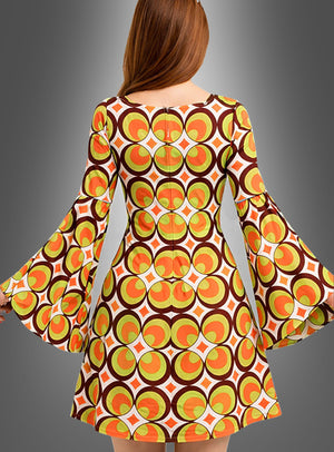 Vor einem grauen Hintergrund ist eine Frau mit langen Haaren von hinten zu sehen. Sie trägt das waschbare 70er-Jahre-Retro-Kleid „Nicky“ mit orangefarbenen, gelben und braunen geometrischen Mustern und ausgestellten Ärmeln. Das auffällige 70er-Jahre-Muster macht dieses Kleid zu einem idealen Kostüm für Mottopartys im Vintage-Stil.