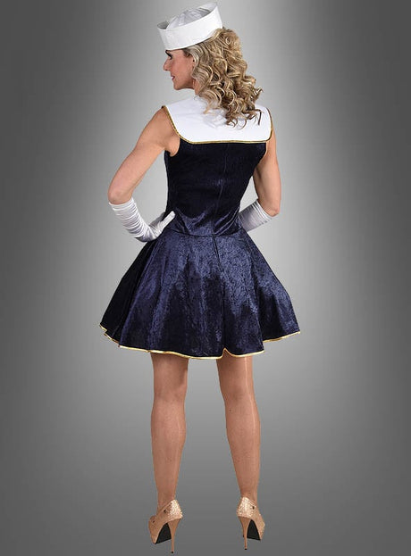 Eine Person, die ein marineblaues Matrosin-Kostümkleid mit weißen Handschuhen, einer weißen Matrosenmütze und hohen Absätzen trägt, steht mit dem Rücken zur Kamera vor einem grauen Hintergrund mit Farbverlauf – eine elegante Wahl für Karnevalskostüme.