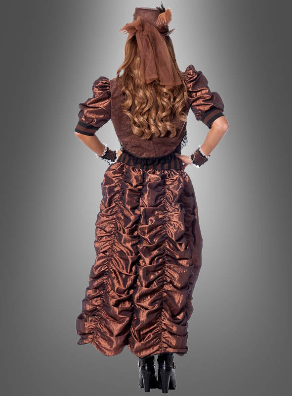Eine Person, die das „Sexy Steampunk“-Kleid und den dazu passenden Hut trägt, steht mit den Händen in den Hüften vor einem grauen Hintergrund, den Rücken zur Kamera gewandt, und verkörpert mit diesem einzigartigen Damenkostüm die viktorianische Mode.