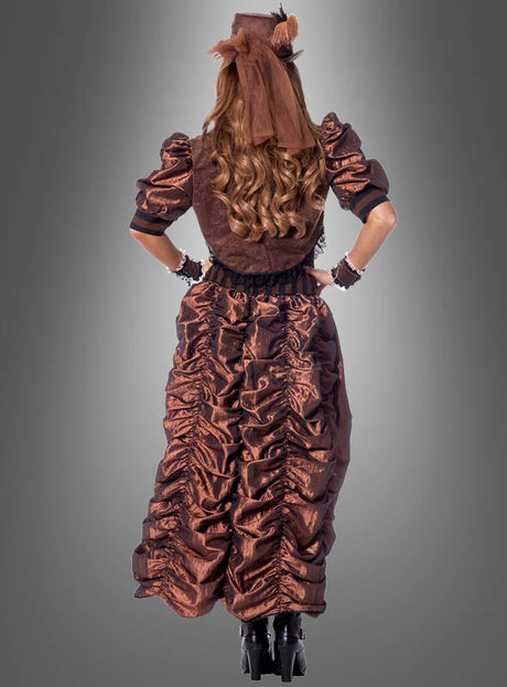Eine Person, die das „Sexy Steampunk“-Kleid und den dazu passenden Hut trägt, steht mit den Händen in den Hüften vor einem grauen Hintergrund, den Rücken zur Kamera gewandt, und verkörpert mit diesem einzigartigen Damenkostüm die viktorianische Mode.
