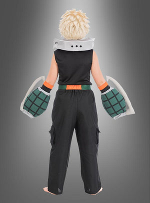 Eine Person mit einer stacheligen blonden Perücke, einem schwarzen, ärmellosen Oberteil, einer schwarzen Hose und großen grünen Handschuhen – ideal für ein Katsuki-Bakugo-Kostüm für Kinder aus „My Hero Academia“ – steht barfuß mit dem Rücken zur Kamera vor einem grauen Hintergrund mit Farbverlauf.