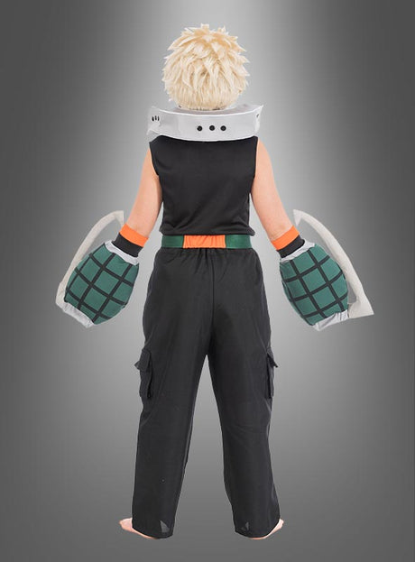 Eine Person mit einer stacheligen blonden Perücke, einem schwarzen, ärmellosen Oberteil, einer schwarzen Hose und großen grünen Handschuhen – ideal für ein Katsuki-Bakugo-Kostüm für Kinder aus „My Hero Academia“ – steht barfuß mit dem Rücken zur Kamera vor einem grauen Hintergrund mit Farbverlauf.