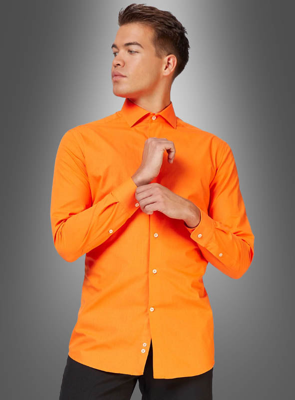 Eine Person, die das orangefarbene „Klassisches Herrenhemd“ trägt – ein langärmeliges Hemd mit Knöpfen und einem figurbetonten Schnitt –, steht vor einem grauen Hintergrund mit Farbverlauf und blickt zur Seite, während sie einen Knopf in der Nähe des Kragens zuknöpft.