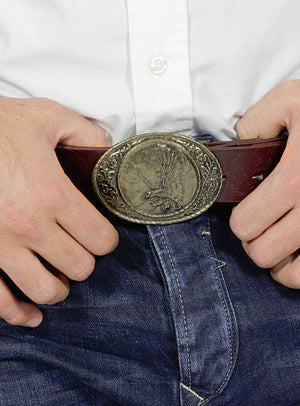 Eine Person in blauen Jeans und einem weißen Hemd, die ein „Pistolengürtel Cowboy Western Holster“ mit einer großen ovalen Schnalle mit Adlermotiv trägt.