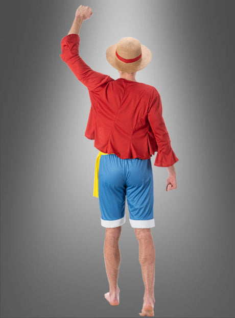 Im Ruffy-Kostüm für Erwachsene aus der Serie „One Piece“ – mit Strohhut, rotem Hemd und blauen Shorts – ist dieser Look mit nackten Füßen und einem erhobenen Arm vor einem grauen Hintergrund mit Farbverlauf ideal für alle, die ein authentisches Monkey D. Ruffy-Kostüm oder ein kreatives „One Piece“-Kostüm suchen.