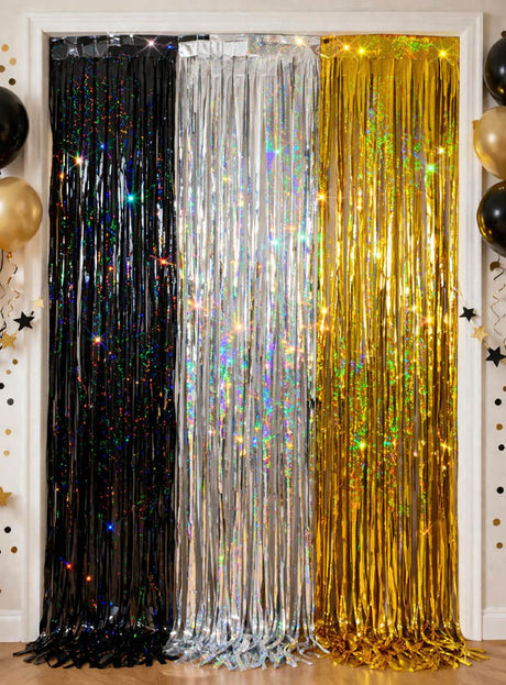 Drei „Glitter Lametta Vorhang“-Vorhänge in den Maßen 100 x 250 cm in den Farben Schwarz, Silber und Gold hängen in einer Türöffnung und sorgen für einen schillernden Silvester-Effekt, wobei schwarze und goldene Luftballons sowie Sternendekorationen beide Seiten schmücken.