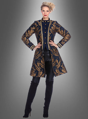 Vor einem schlichten grauen Hintergrund steht eine Frau, die eine lange, marineblaue „Luxus Barock Brokat Jacke Damen“ mit Goldstickerei trägt, dazu schwarze Hosen und schwarze Stiefel mit hohen Absätzen.