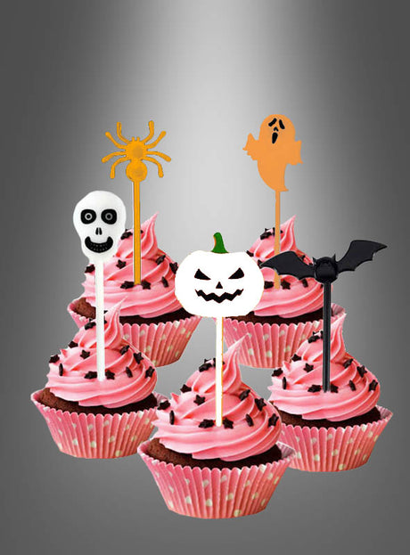 Zehn „10 Stück Cocktailspieße Halloween“ mit rosa glasierten Cupcakes, jeweils verziert mit einem Halloween-Motiv – Spinne, Geist, Totenkopf, Kürbis und Fledermaus – eignen sich perfekt als Fingerfood-Deko oder Halloween-Tischdekoration vor einem grauen Hintergrund mit Farbverlauf.