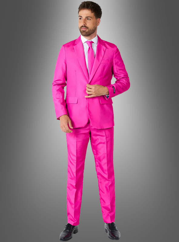 Vor einem grauen Hintergrund mit Farbverlauf steht ein Mann, der den „Pinker Anzug mit Krawatte“ von Suitmeister trägt, ergänzt durch ein weißes Hemd und schwarze Schuhe.