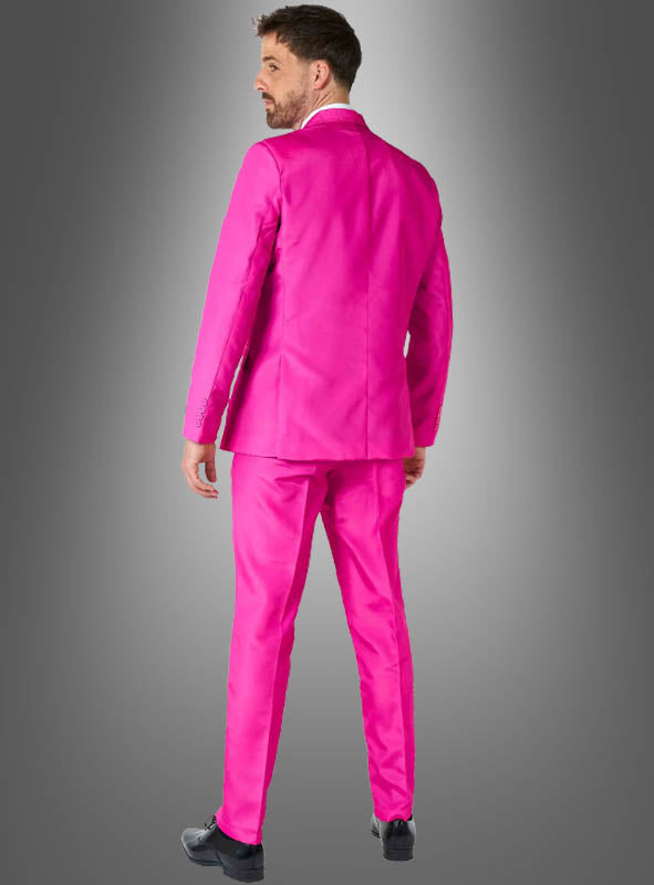 Vor einem grauen Hintergrund mit Farbverlauf steht ein Mann mit dem Rücken zur Kamera; er trägt einen „Pinker Anzug mit Krawatte“ von Suitmeister und schwarze Schuhe.