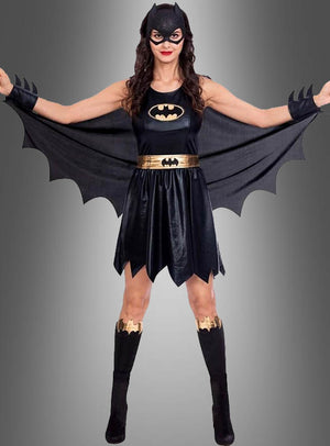 Eine Person im Batgirl-Kostüm für Damen – komplett mit Maske, geflügeltem Umhang, schwarzem Kleid, goldenem Gürtel und passenden schwarz-goldenen Stiefeln – steht mit ausgestreckten Armen vor einem grauen Hintergrund und ist damit die ideale Wahl für Fans, die nach einem kultigen DC-Comics-Kostüm suchen.