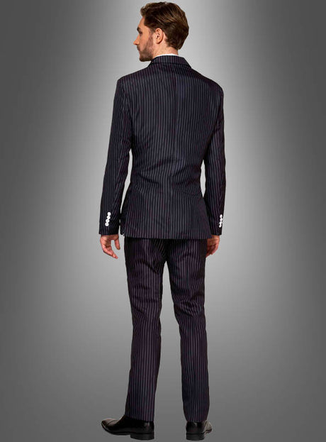 Ein Mann steht mit dem Rücken zur Kamera und trägt einen dunklen Nadelstreifen-Anzug von Suitmeister sowie schwarze Schuhe vor einem grauen Hintergrund mit Farbverlauf – perfekt für alle, die auf der Suche nach einem authentischen Mafia-Kostüm oder einem Halloween-Outfit sind.